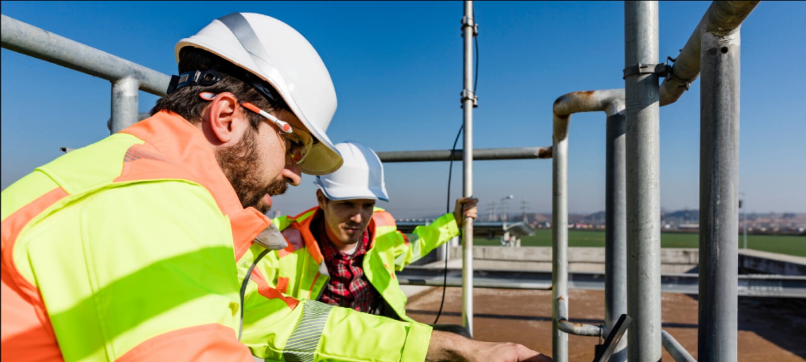 Two water resources engineers looking at a laptop while on a job site.