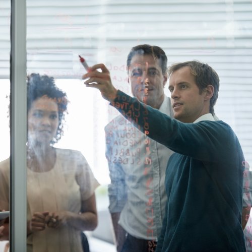 Three applied statistics professionals solving a problem on a board.