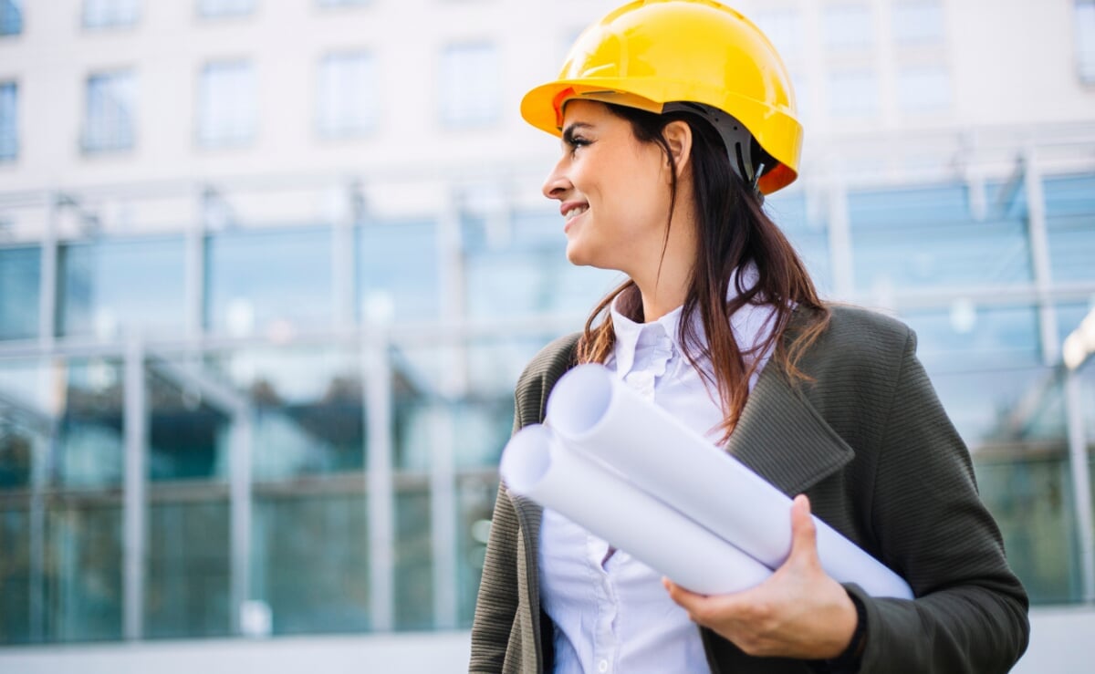Female civil engineer wearing a hard hat holds some plans.