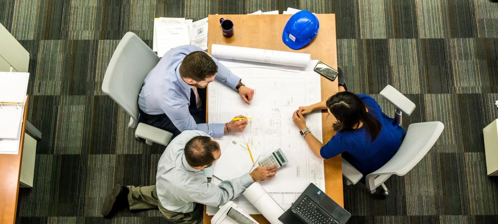 Three people sitting around a table figuring out an engineering plan.