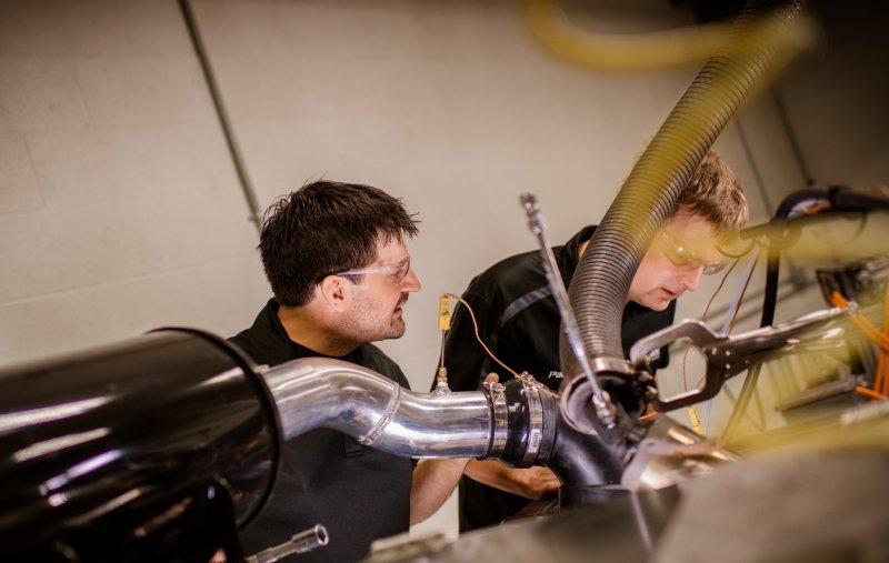 Two engineers working on a combustion engine.