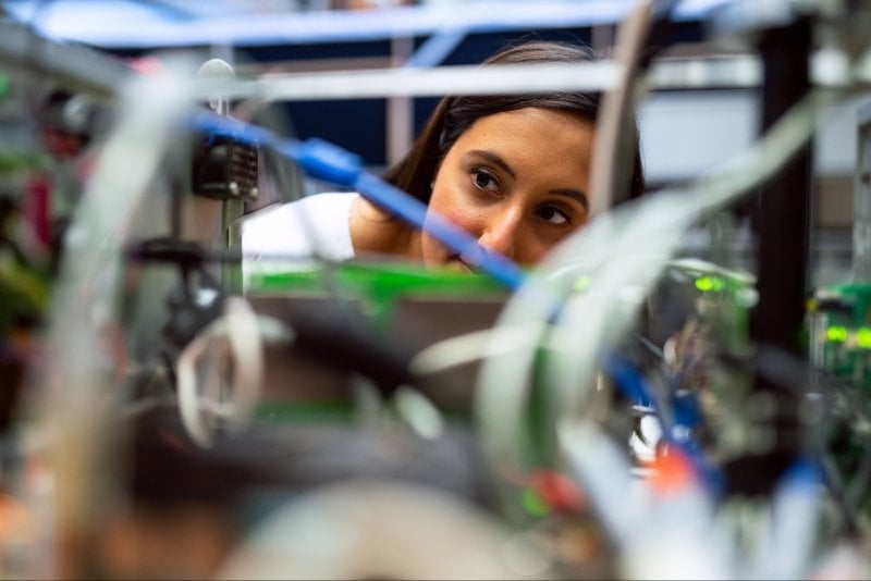 Female engineer looking at a machine with lots of wires.