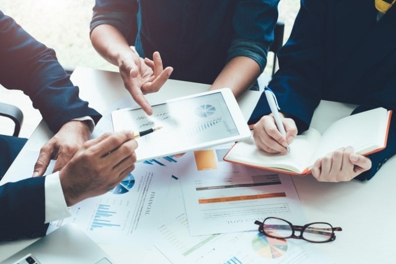 Business professionals around a table looking at some charts.