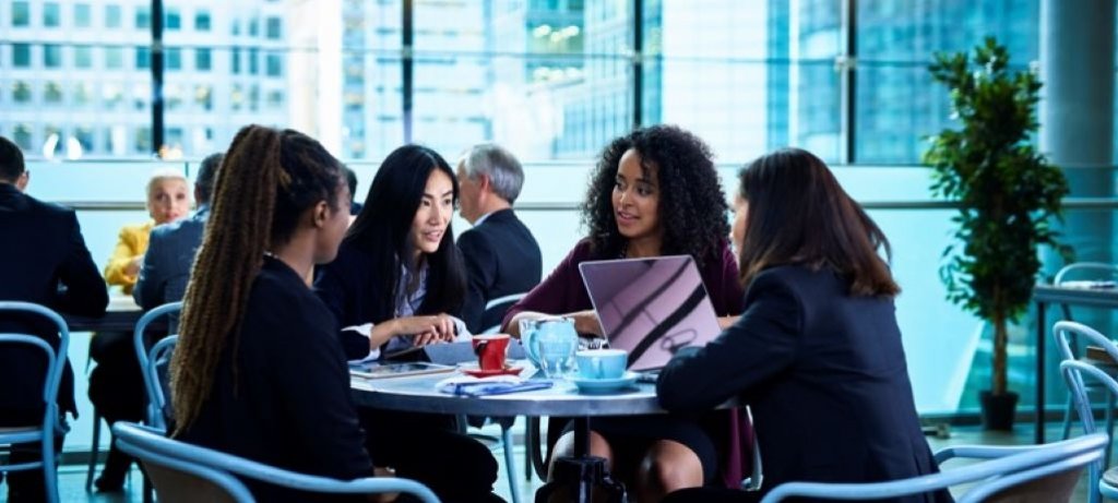 Professional women talking around a table.