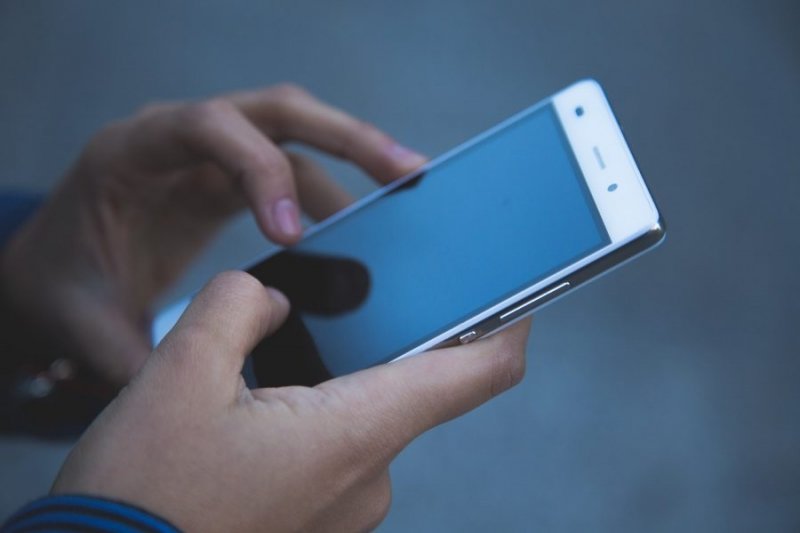 Person holding smartphone while getting help from a virtual mental health assistant.