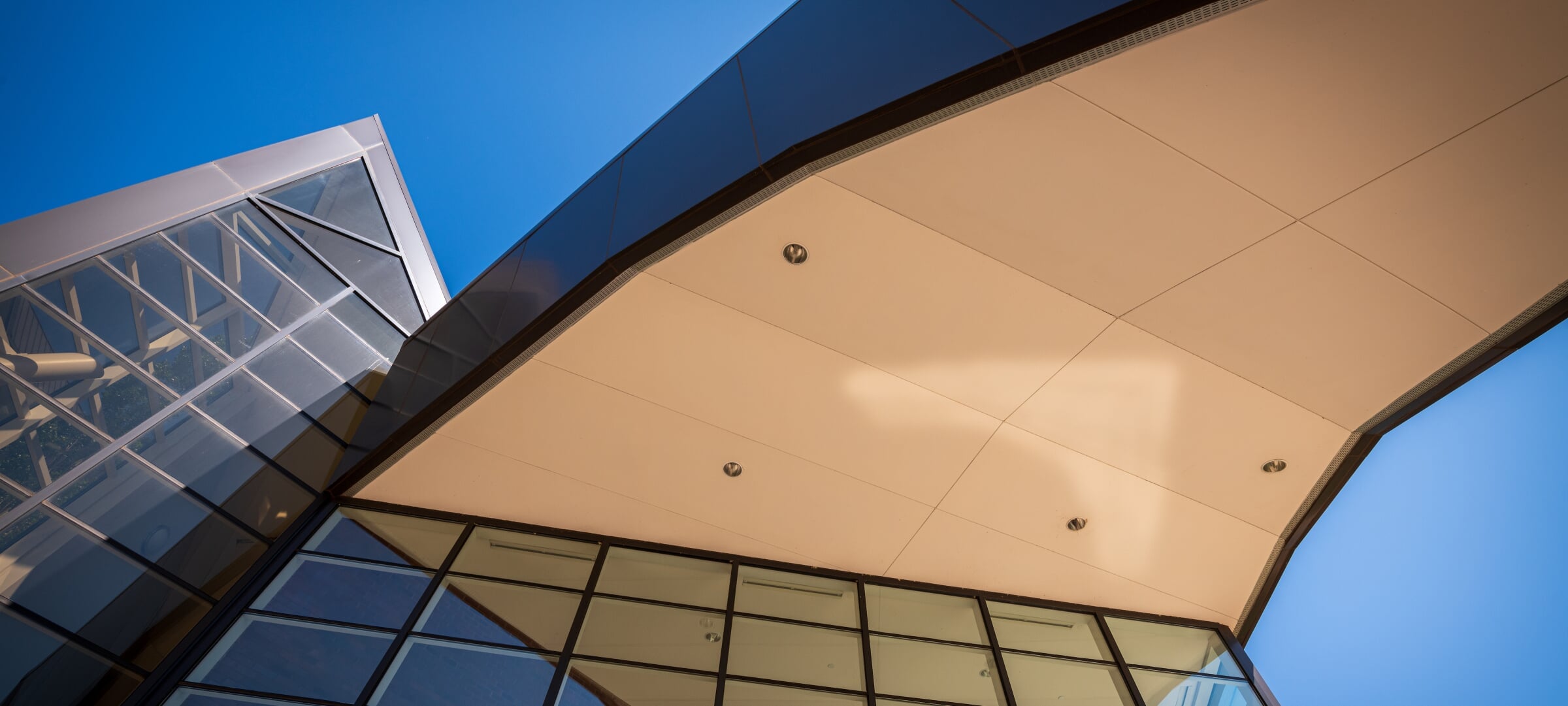 Looking up towards the underside of an oddly-shaped architectural jut out from the Rozsa Center.