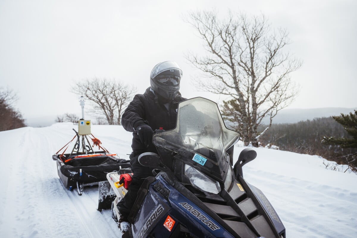 Graduate student on a snowmobile pulling a water level monitor