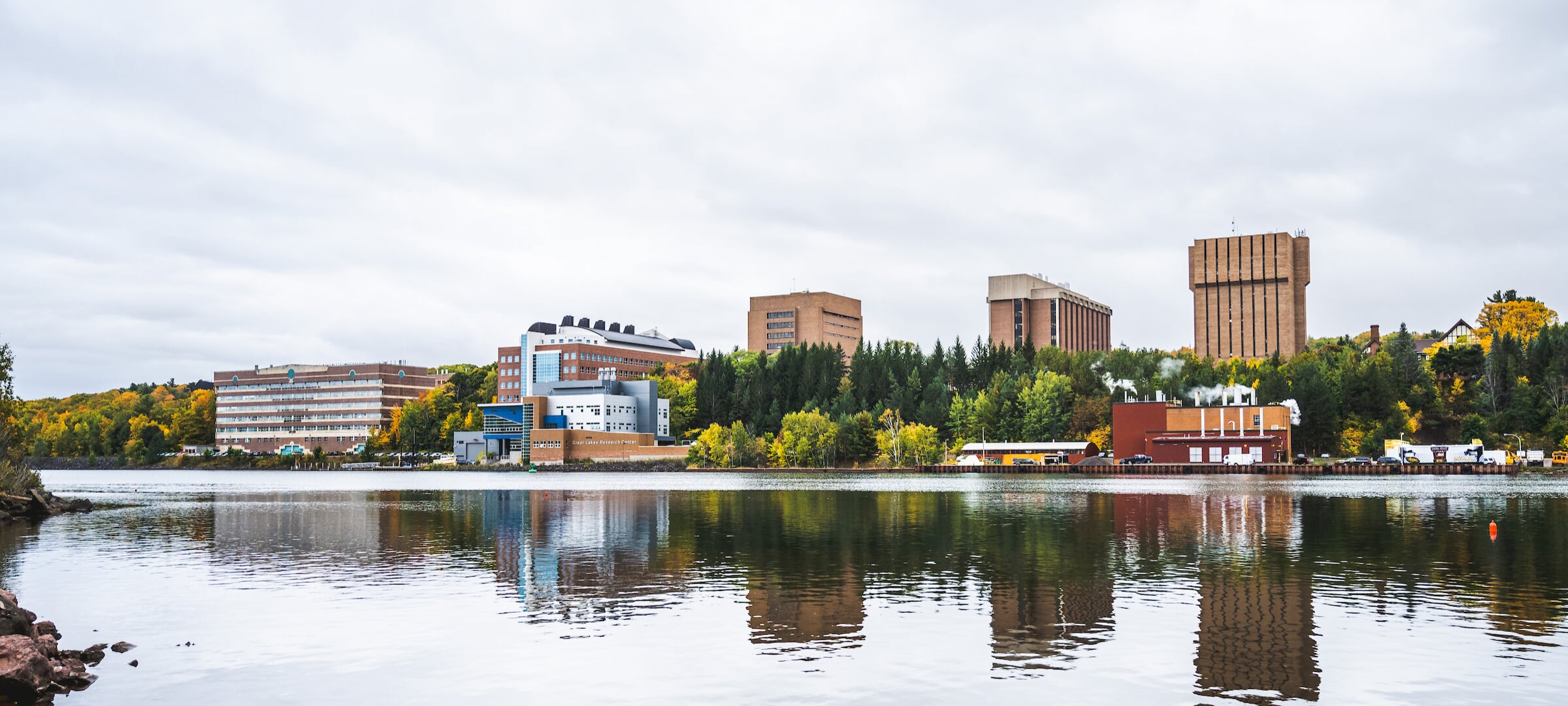 A panoramic vista of Michigan Tech's campus on the water during the Fall season.
