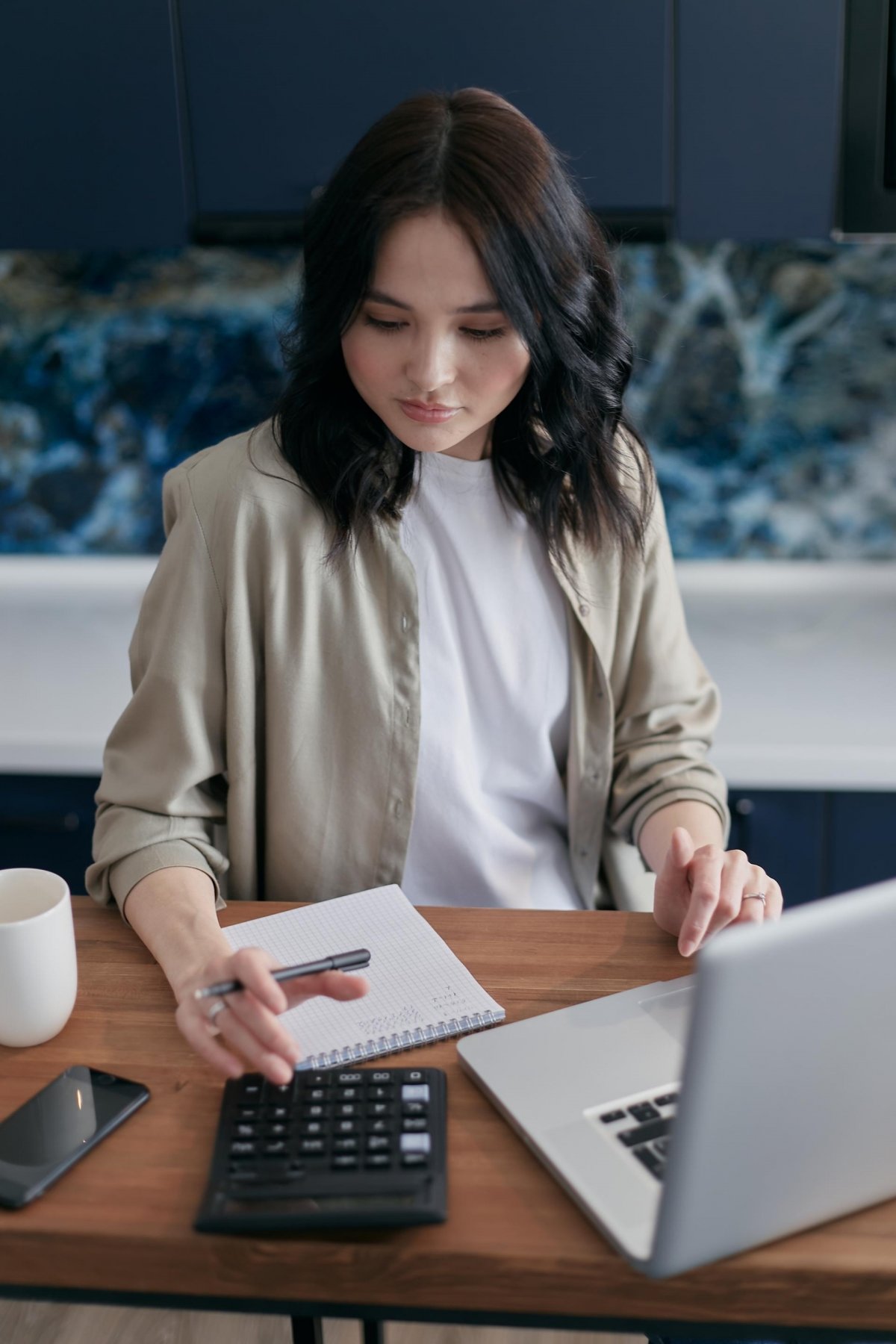 Woman using a calculator while sitting at a desk.