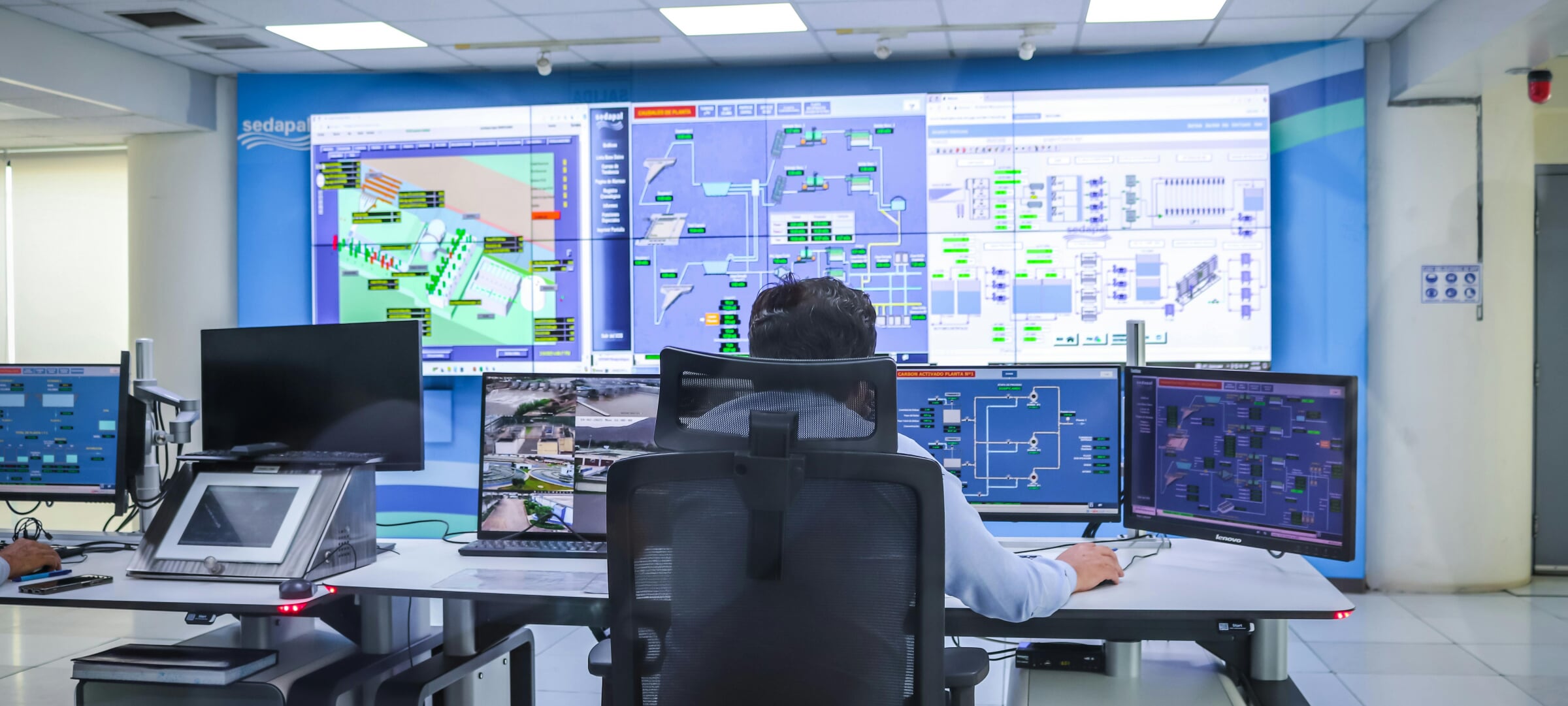 Engineer in a room looking at several control systems on different monitors