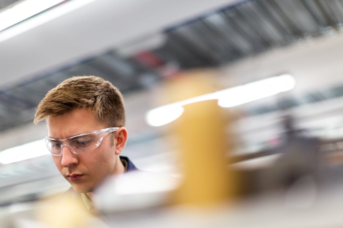 Mechanical engineer working in a shop. The background is blurred.