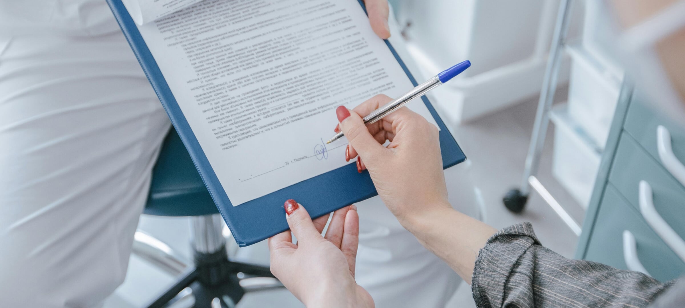 Person signing a waiver while in a doctor's office.