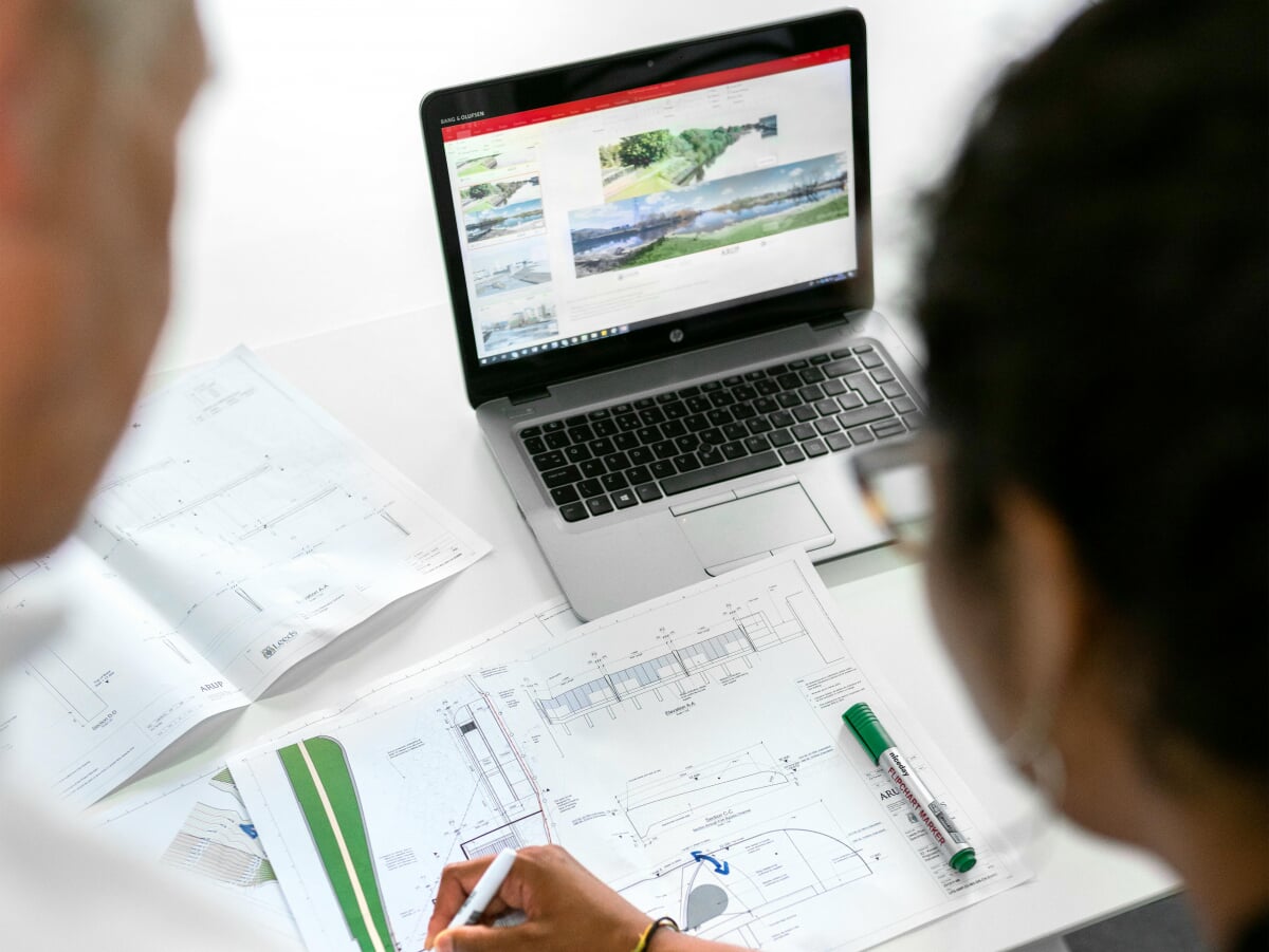 Two water engineers looking over a plan on a laptop.