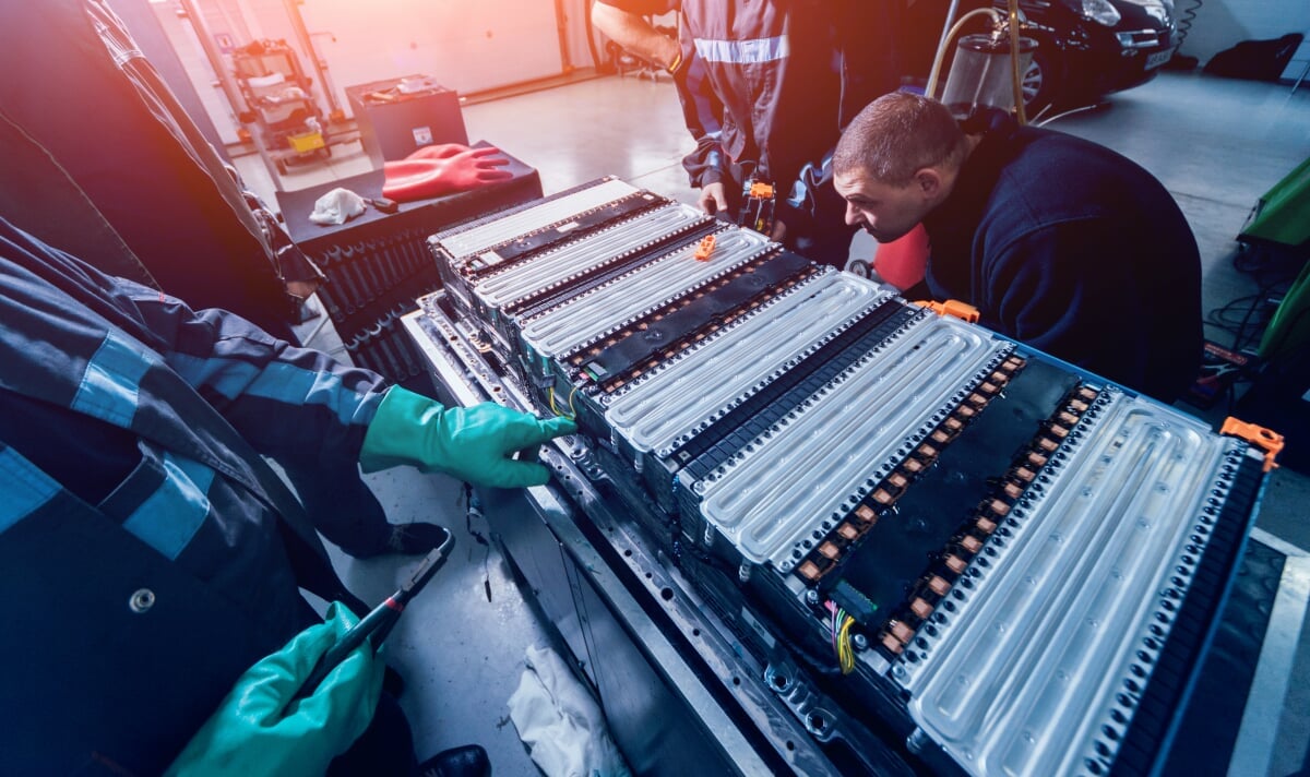 Adobe Stock Image of engineers standing around and looking at a giant electric battery