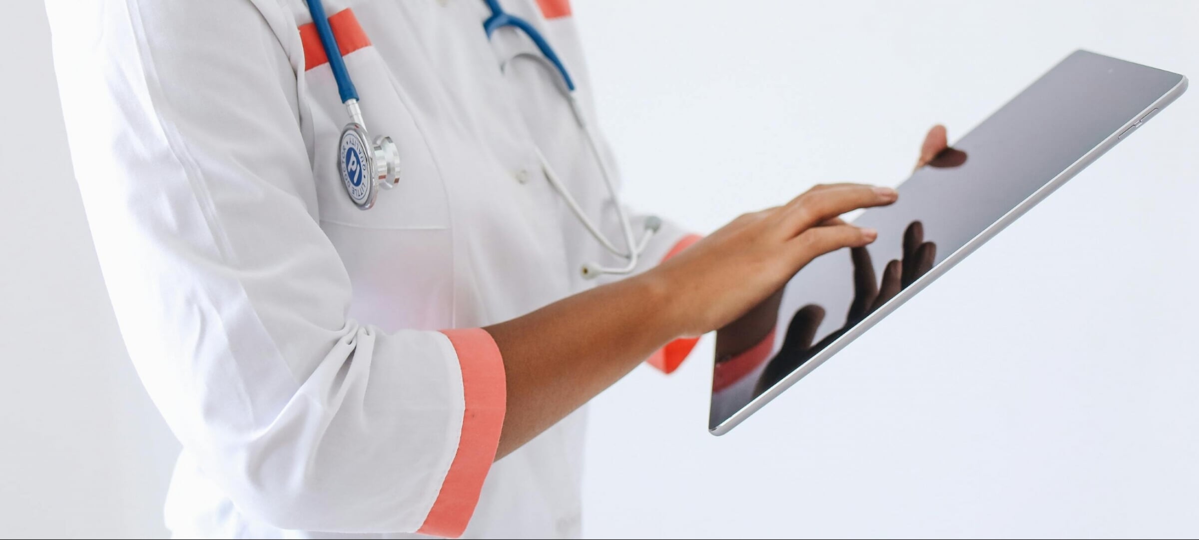 Medical professional wearing a doctor's coat looks at a tablet.