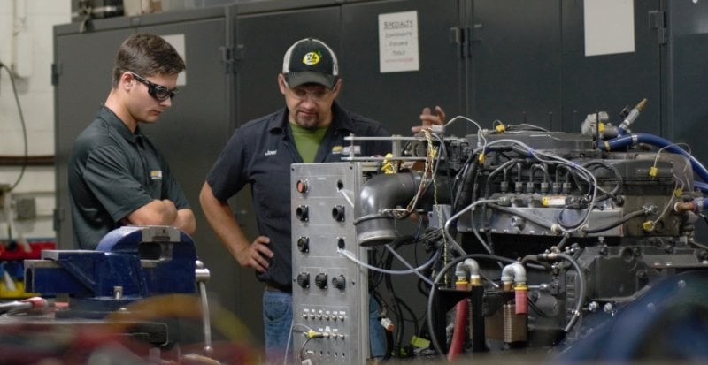 Two engineers in a lab studying on a huge engine.