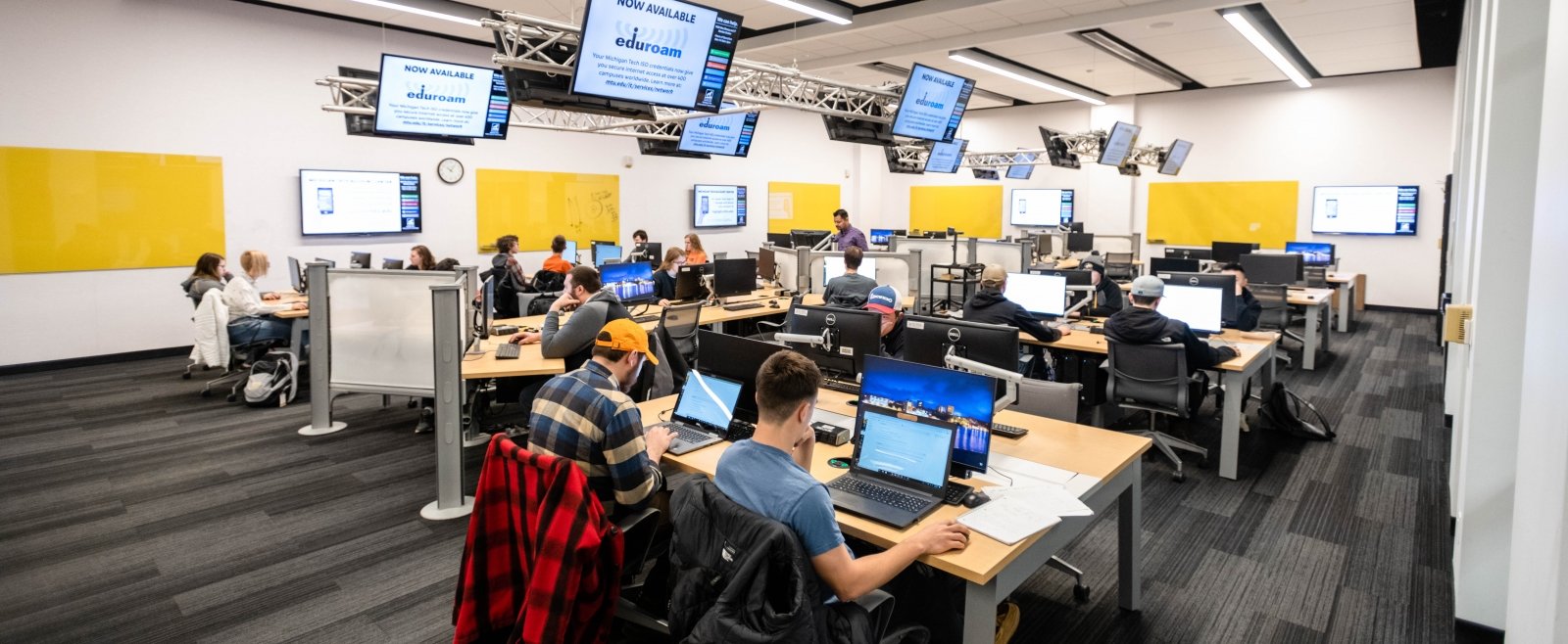 Michigan Tech classroom with students at computers in a room with video screens overhead.