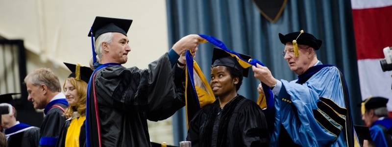 Graduate Student getting hooded by her advisor and the dean for her degree in Forest Science