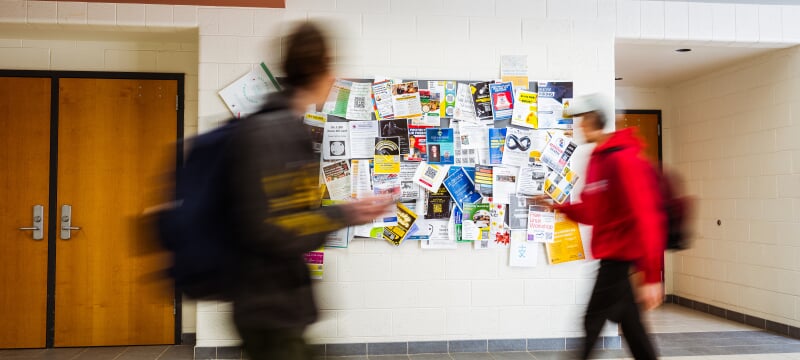 Two people wearing backpacks walking past each other