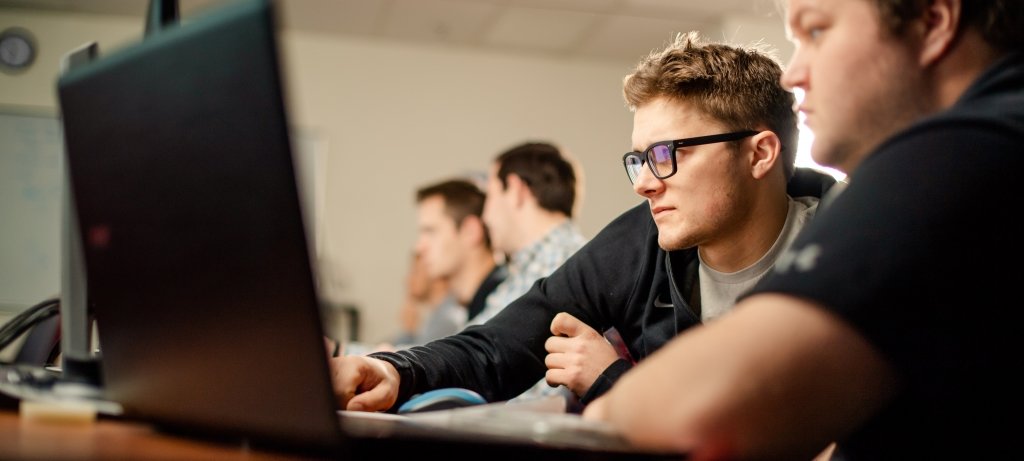 Graduate students sitting at a table with computers and laptops