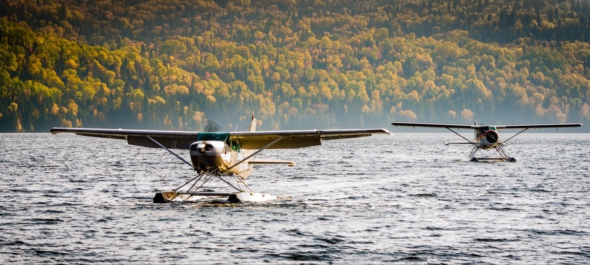 Two sea planes landing on a lake.