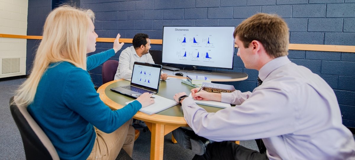 Grad students looking a computers in a classroom.