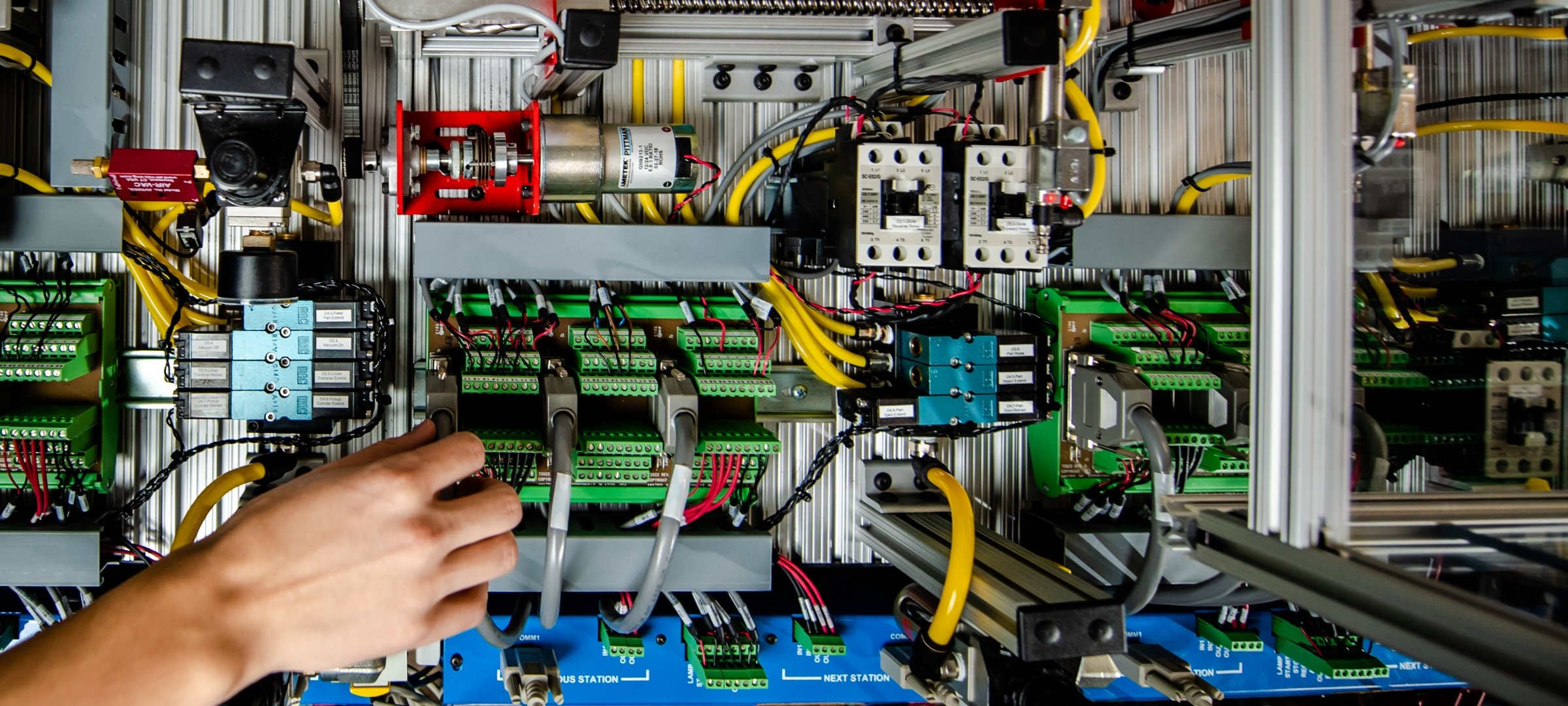 Grad student reaching to adjust a controls circuit box.