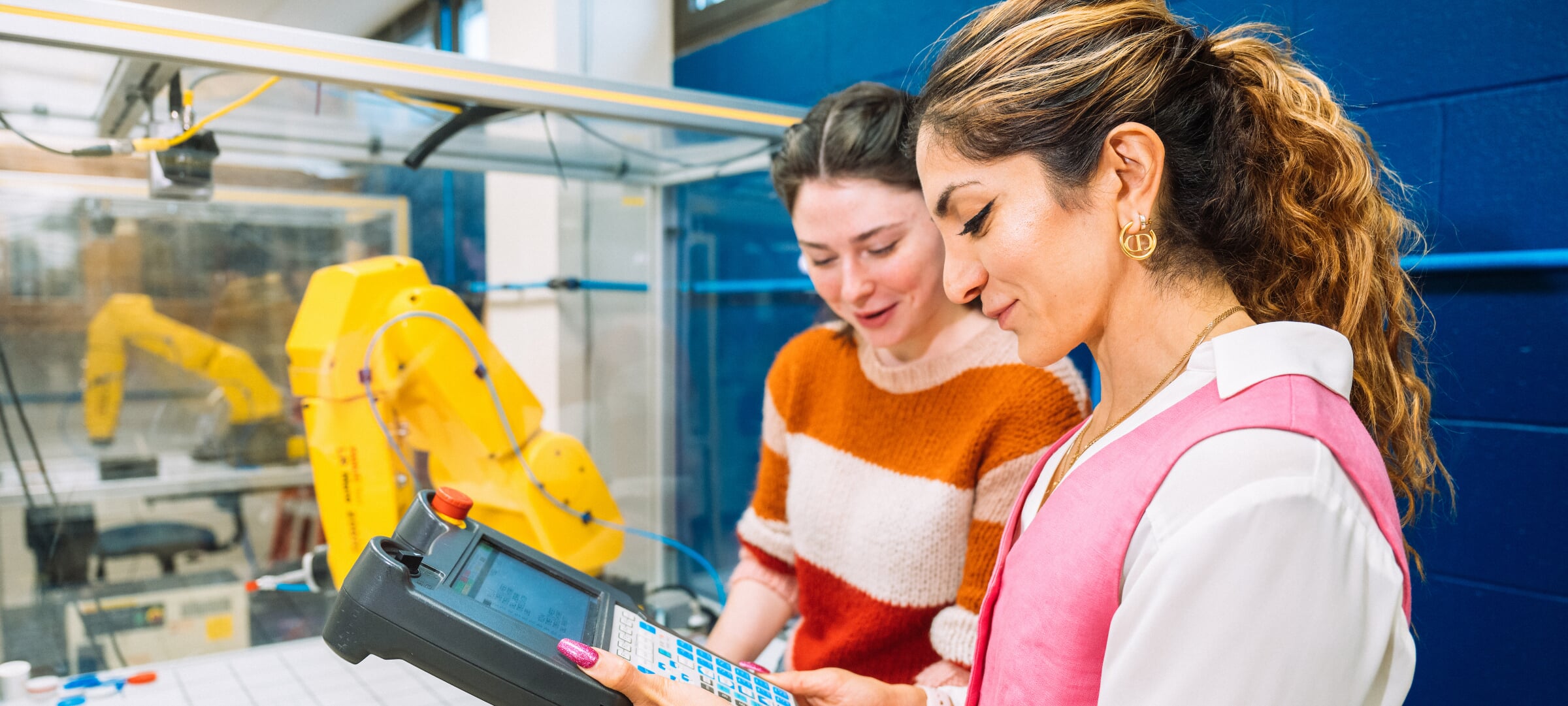 A professor and grad student inspect the control system for a robotic arm.