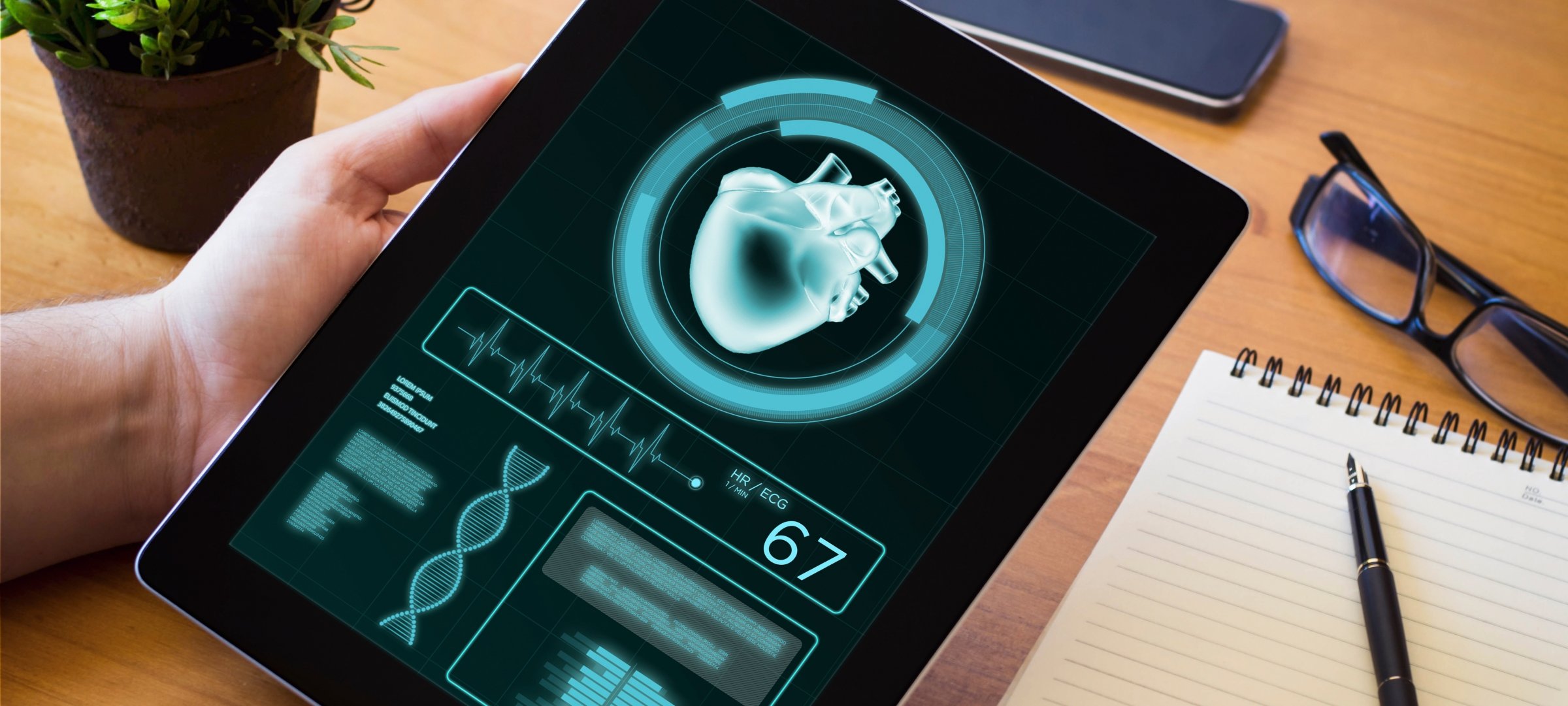 Graduate student sitting at a desk holding an iPad with health and heart data.