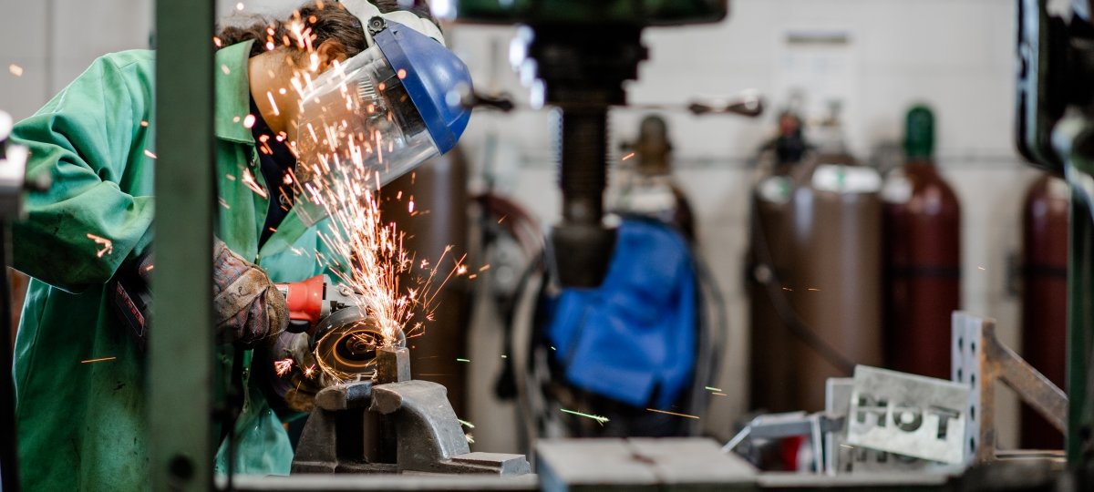 With sparks flying, a researcher using a cutting device to cut metal with protection gear.