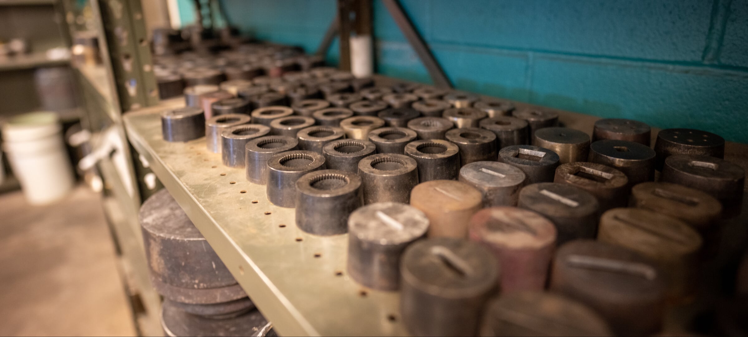 Rows of metal alloy cylinders a few inches high sit on a metal shelf.