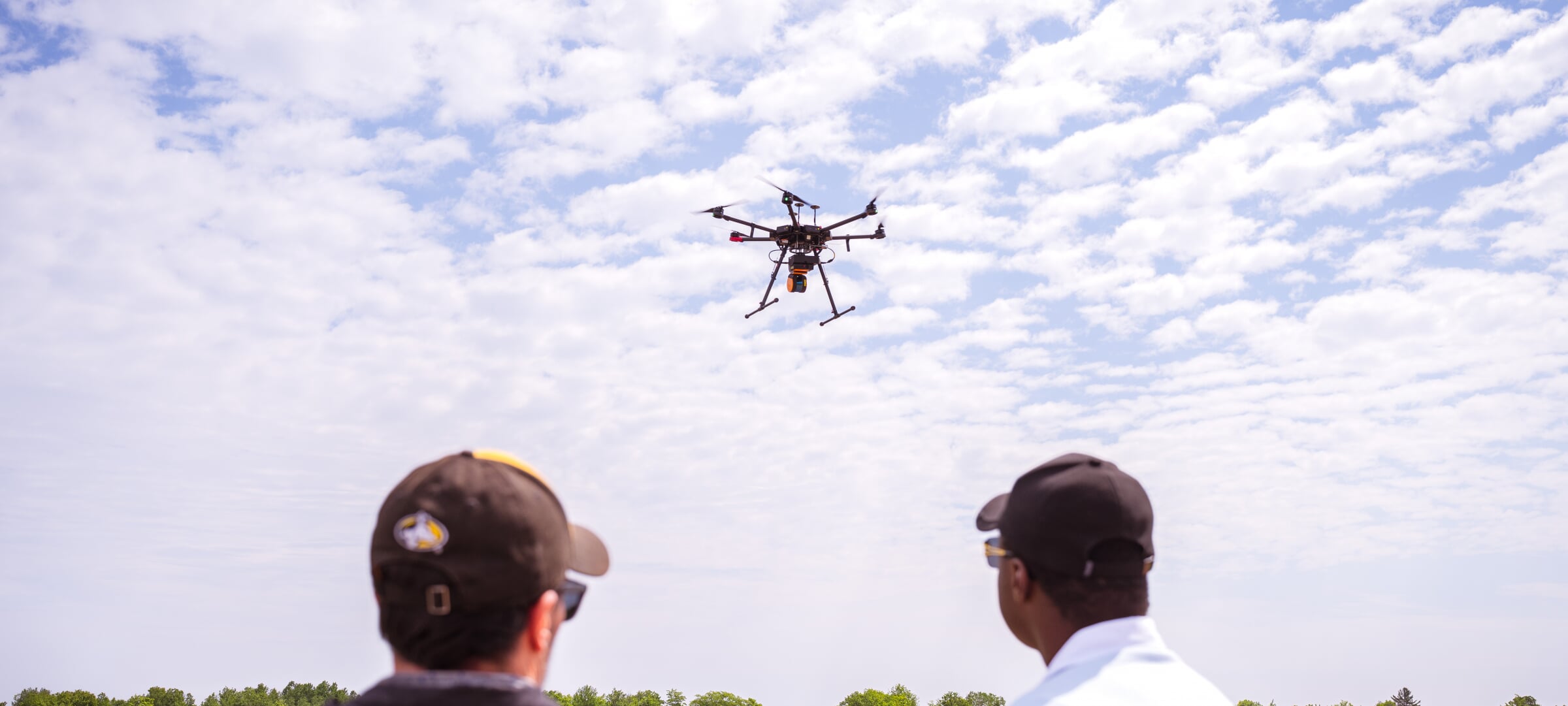 Two researchers looking at flying drone.