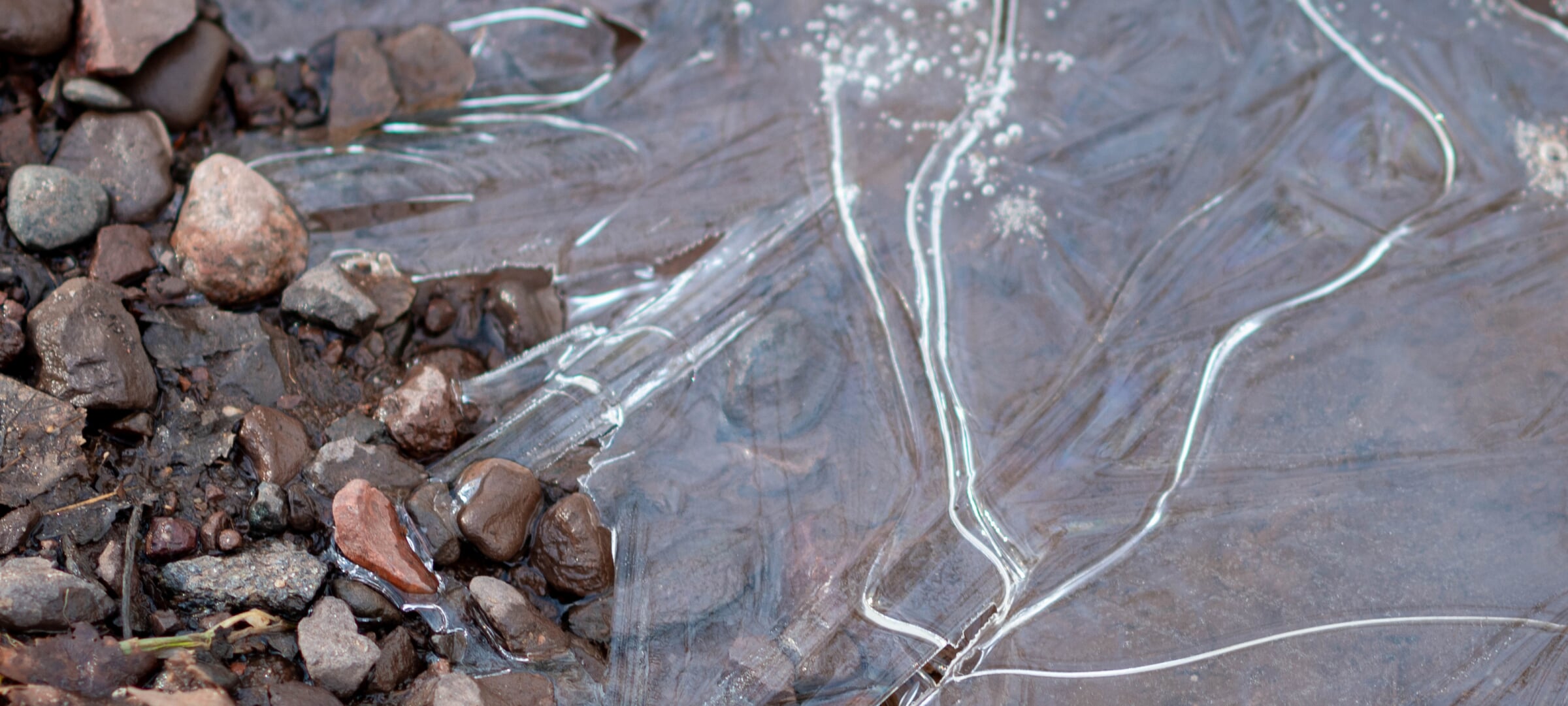 Extreme close-up of an icy streamy and its pebbly bank.