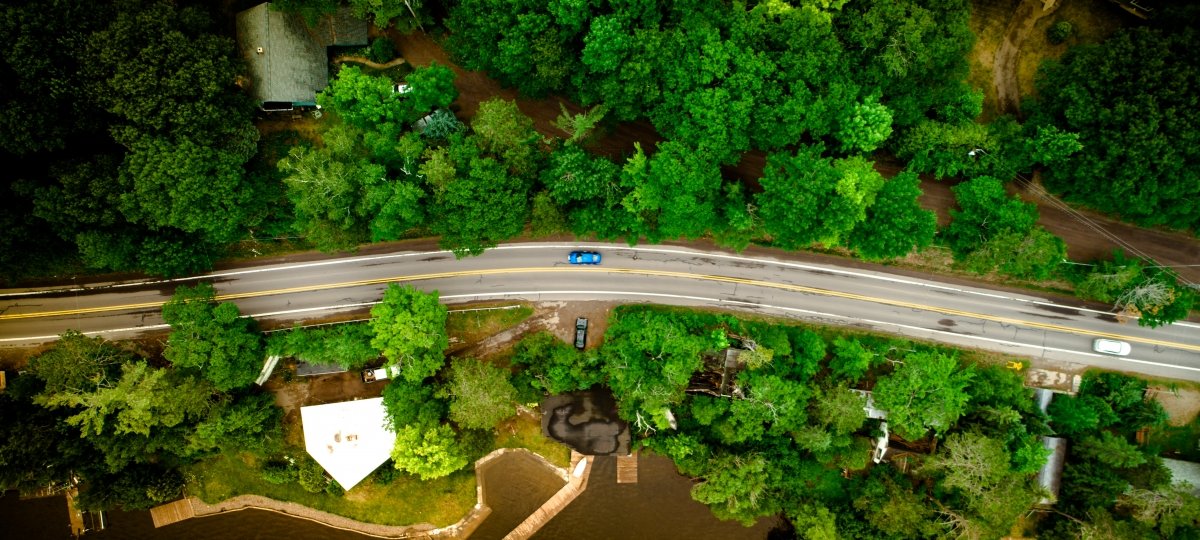 Aerial of a wooded area and highway with cars traveling.