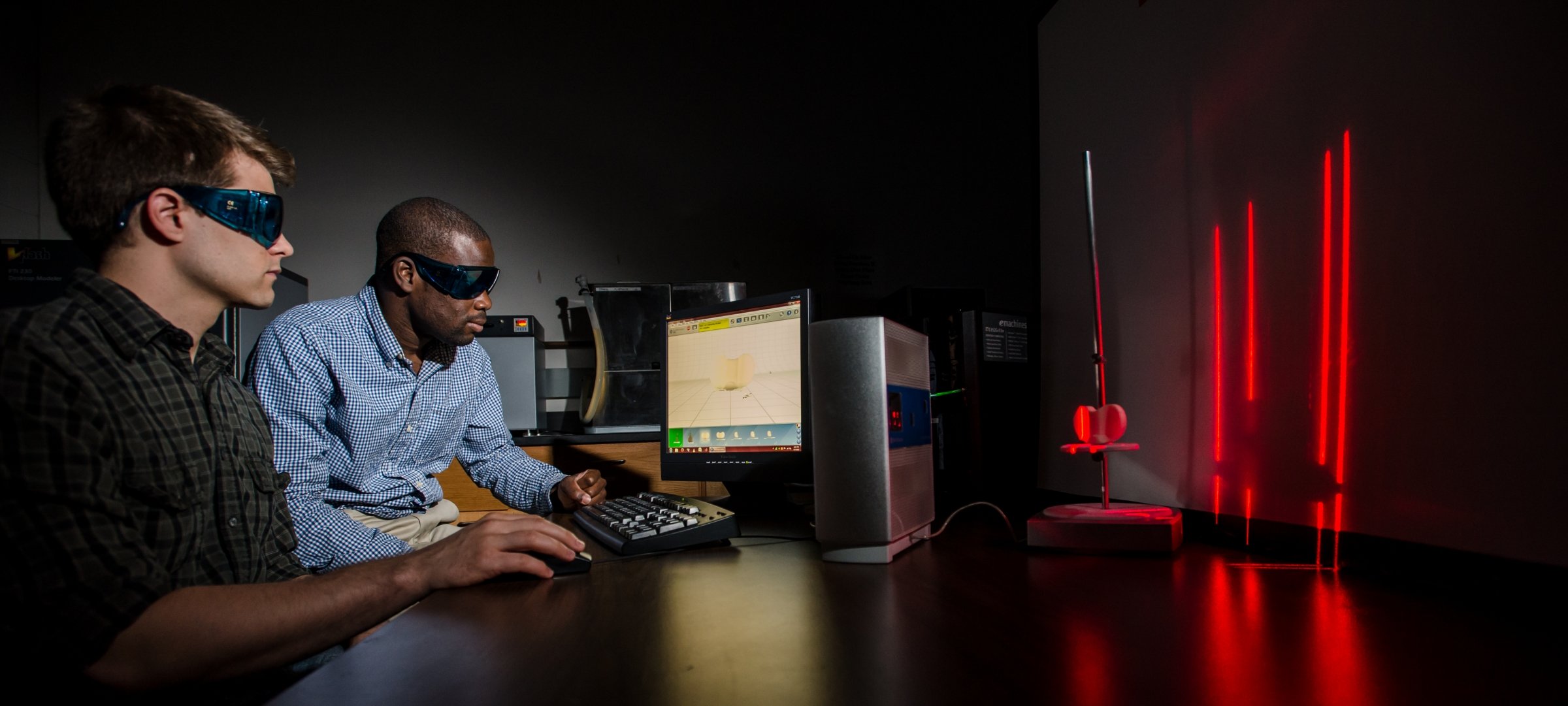 Two grad students with shaded glasses looking at a computer screen.