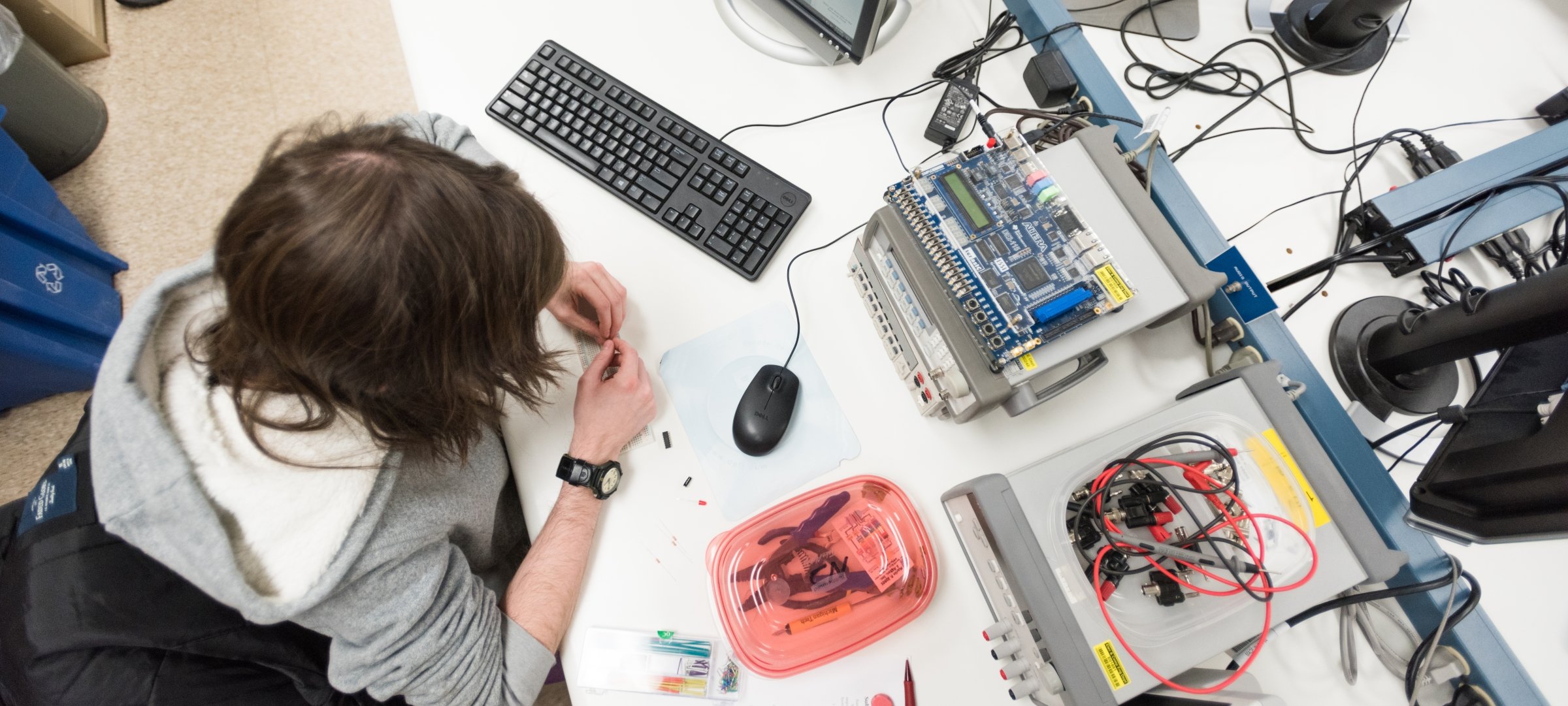 Student sitting at a desk with a computer and electronic materials.