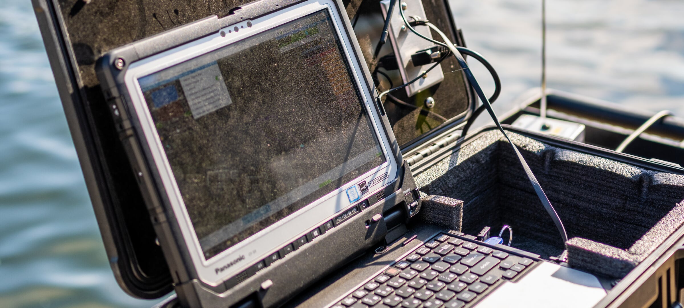 Research laptop hooked up to equipment in front of a waterway.