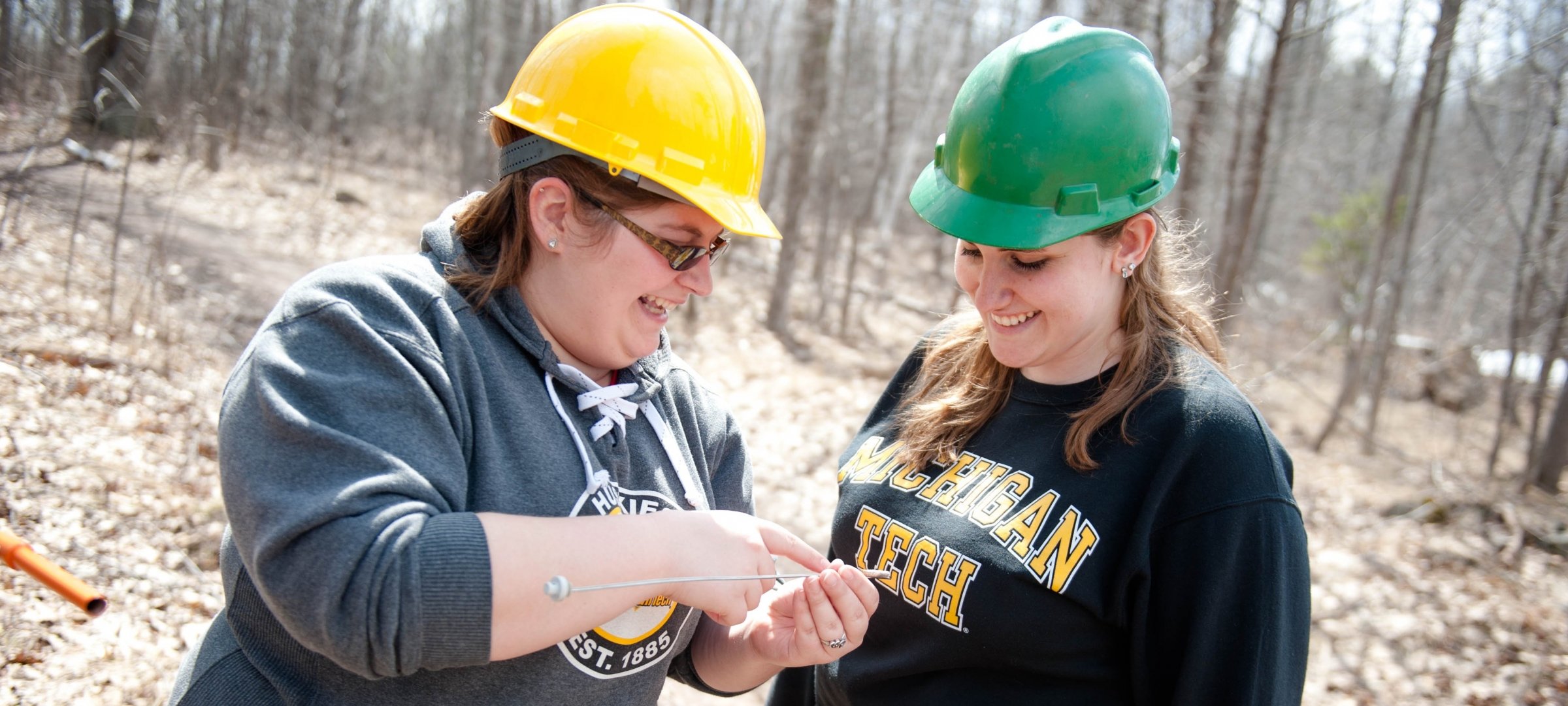 Forestry students standing in a forest, wearing hardhats.