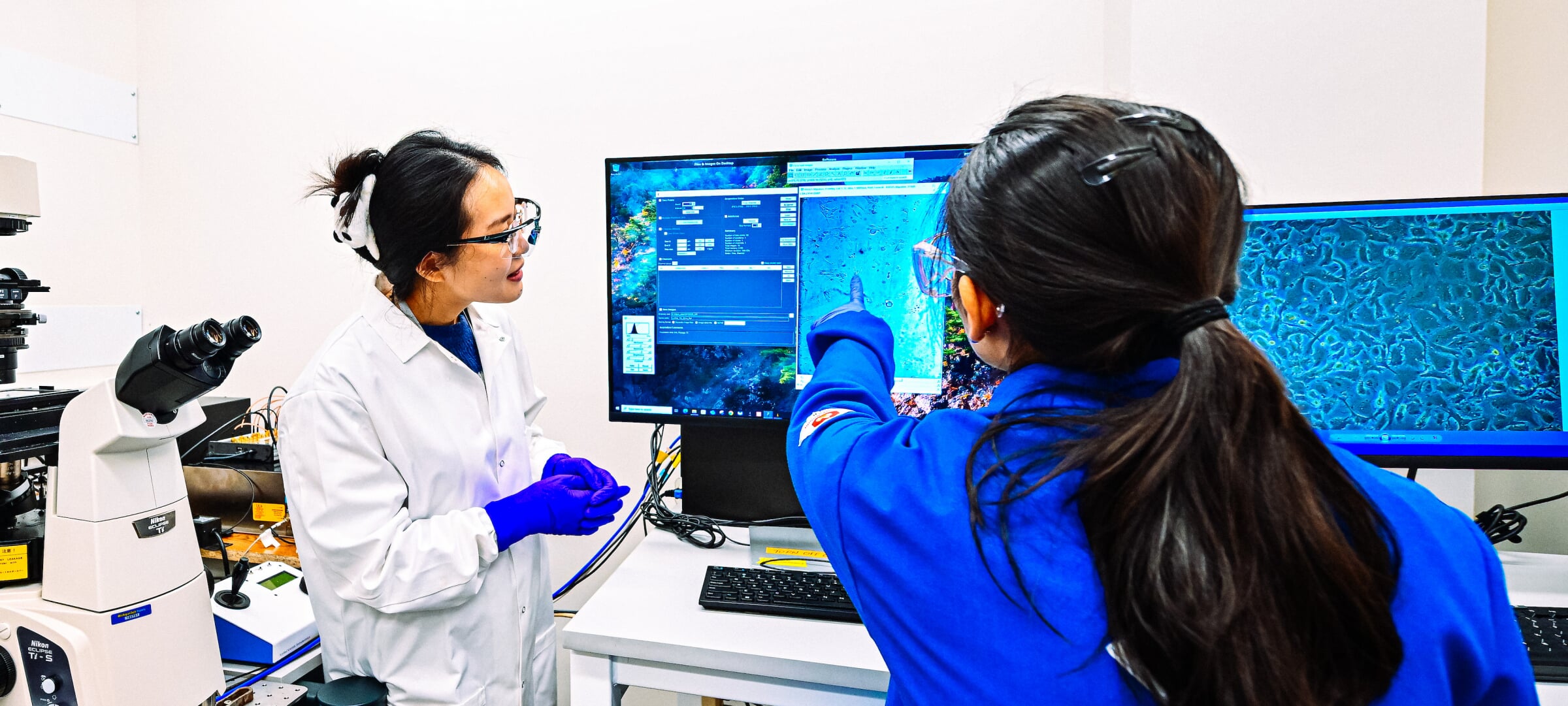 Two students inspect imaging results displayed on desktop monitors.