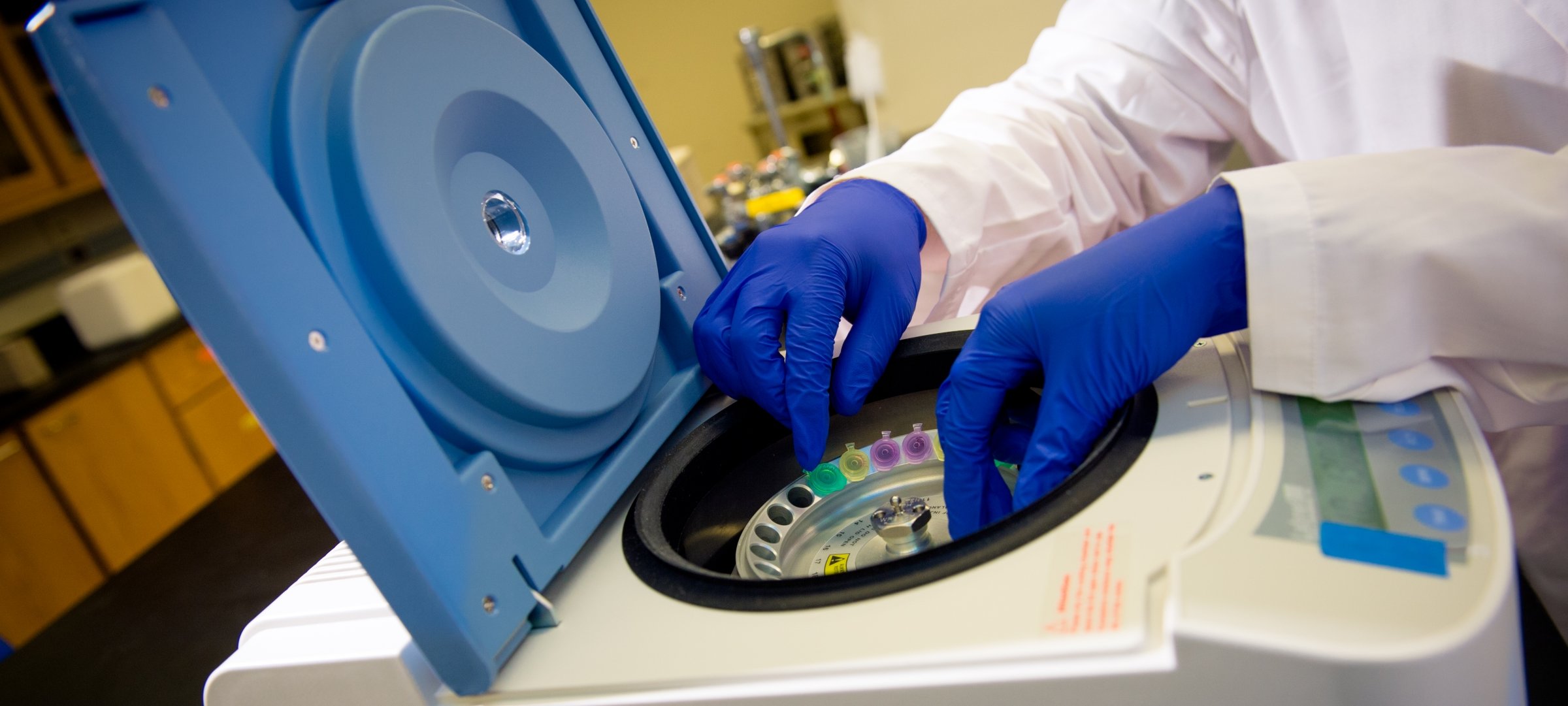 Integrated physiology researcher with gloves running an experiment in a piece of lab equipment