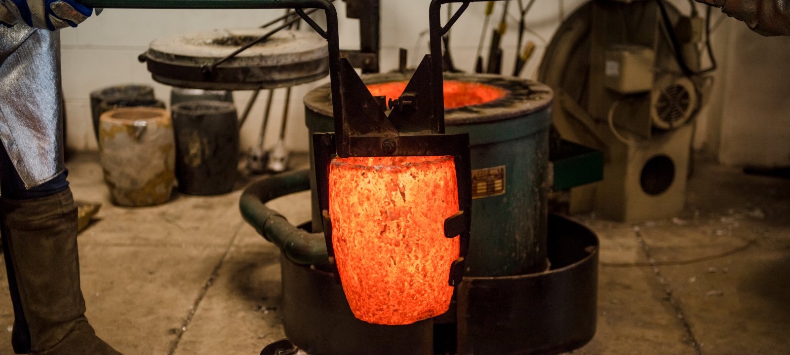 Students working in the foundry, pouring hot material into a mold.