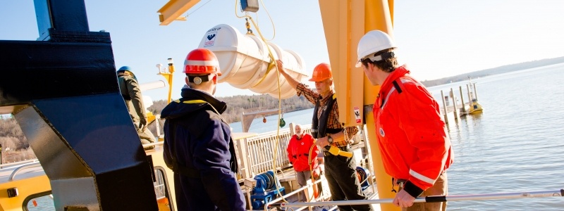 People working with loading boom on boat.