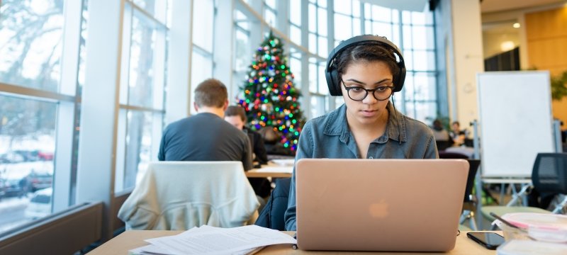 Grad Student with headphones sitting with laptop in library