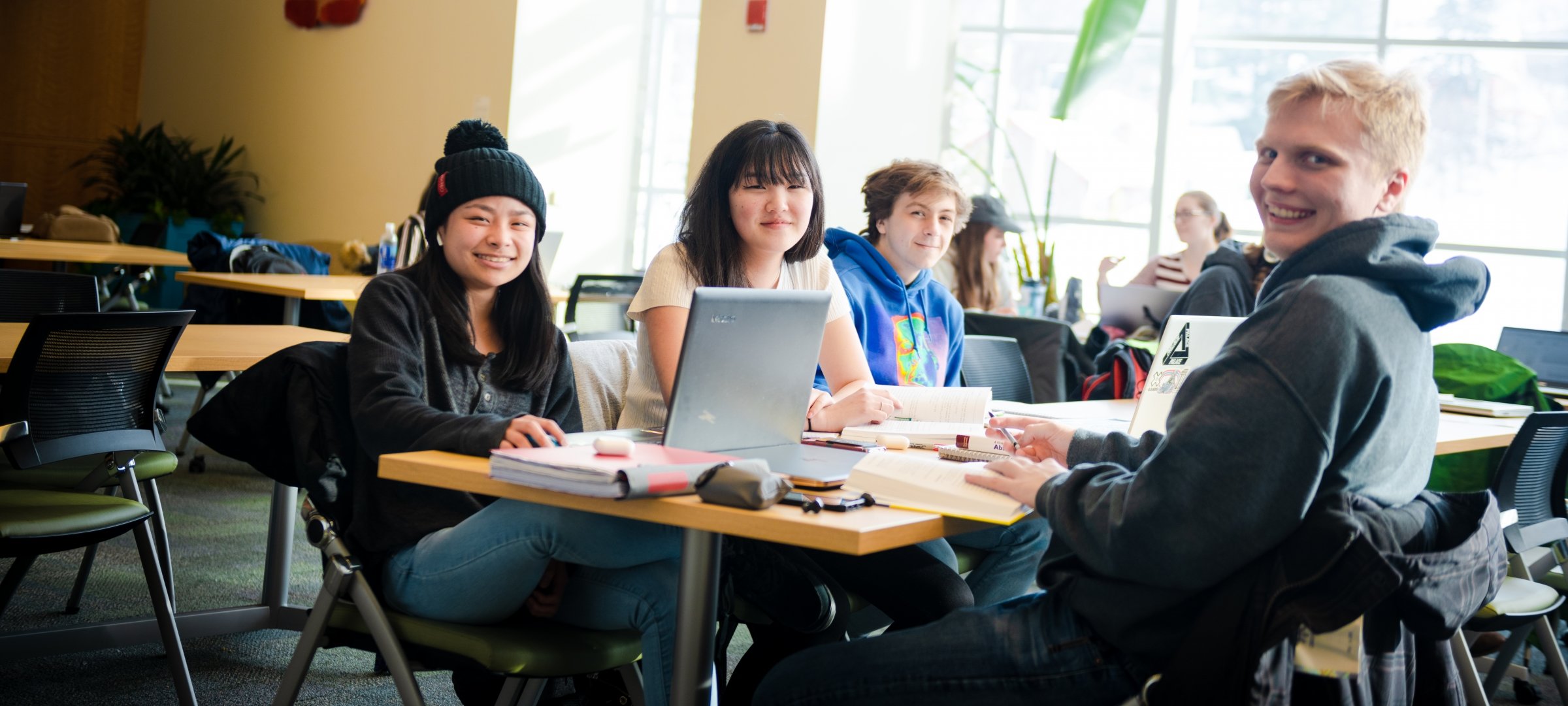 Students sitting in at a table in the Van Pelt Library smiling.