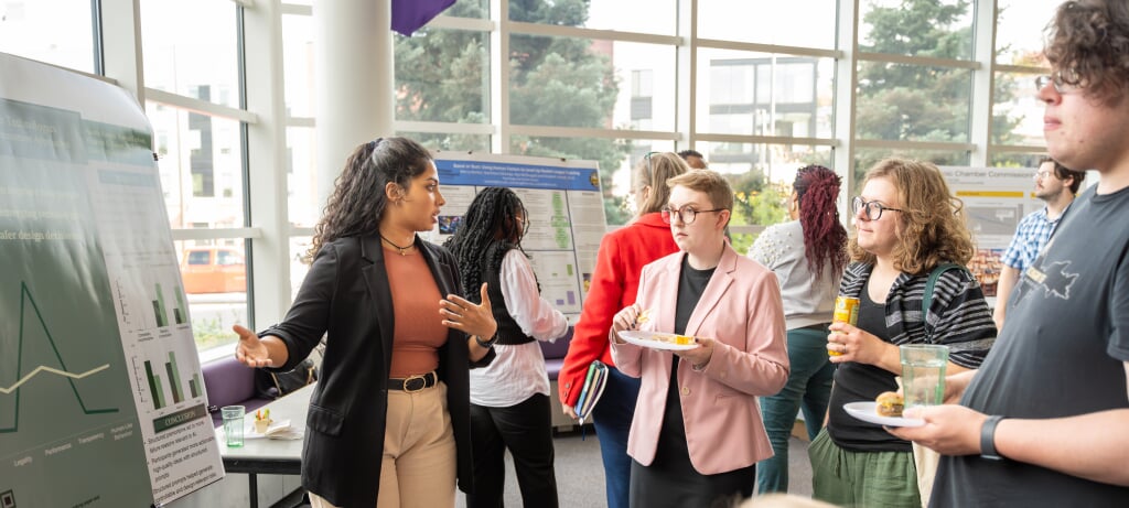 Student presenting a poster to three other students