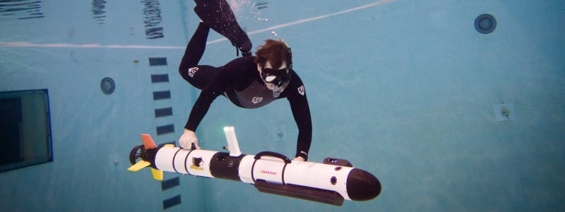 Diver underwater with a subsurface vehicle, tube shaped.