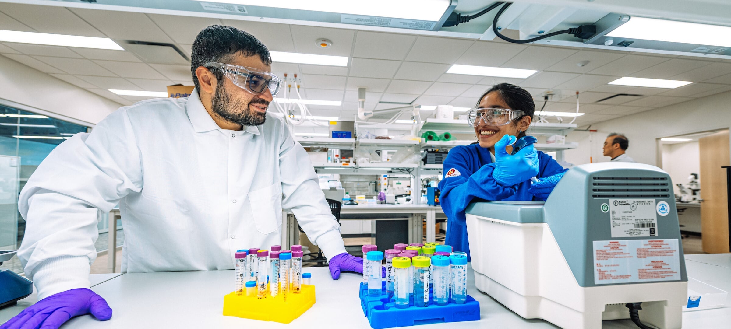 Two graduate students in a lab with protective gear