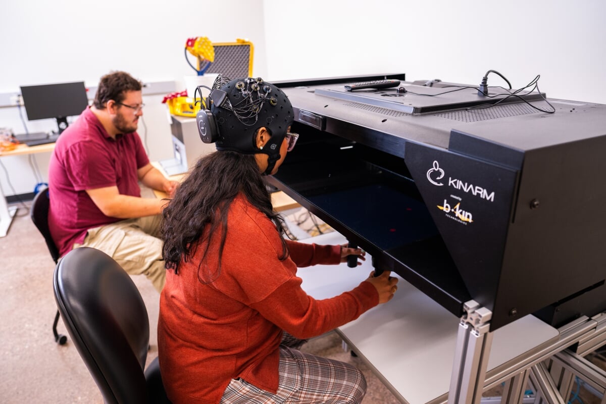 Student using human interaction machine with researcher looking on.
