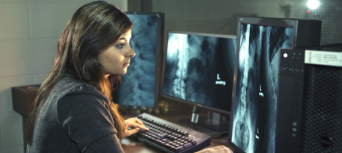 A female student inspects x-rays on multiple computer screens