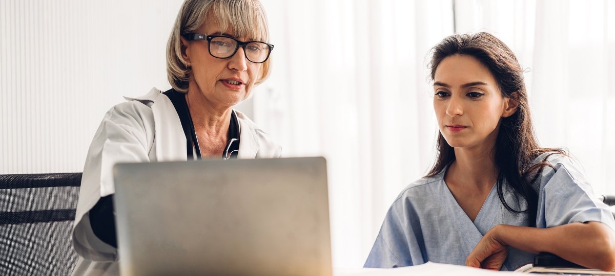 Two medical professionals discuss information on a computer